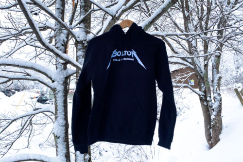 Black hoodie that reads "Bolton Valley Vermont" hangs from a snow covered tree