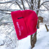 Pink embroidered beanie that reads "Bolton Valley" hanging from a snow covered tree