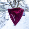 Red embroidered beanie that reads "Bolton Valley" hanging from a snow covered tree